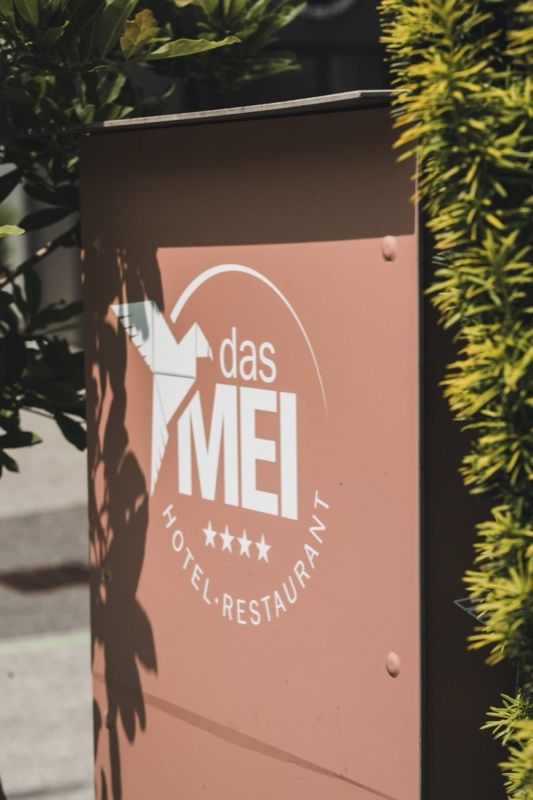Schild „das MEI Hotel · Restaurant“ in Rosé an der Hauswand